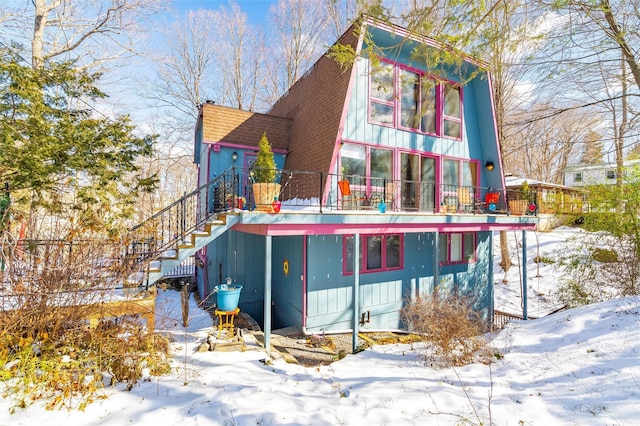 snow covered back of property featuring roof with shingles