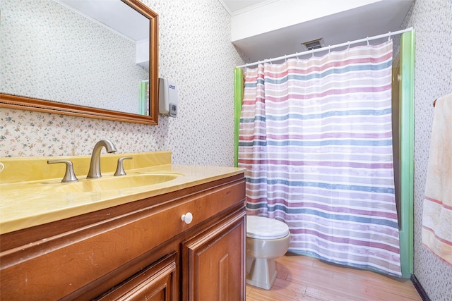 bathroom featuring visible vents, toilet, vanity, wood finished floors, and wallpapered walls