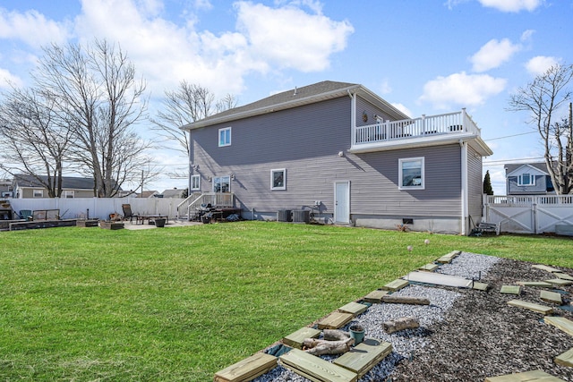 back of house with a gate, a fenced backyard, a lawn, and a balcony