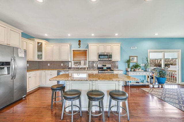 kitchen featuring stainless steel appliances, a center island, glass insert cabinets, and a breakfast bar