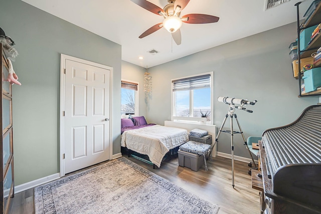 bedroom with baseboards, visible vents, and wood finished floors