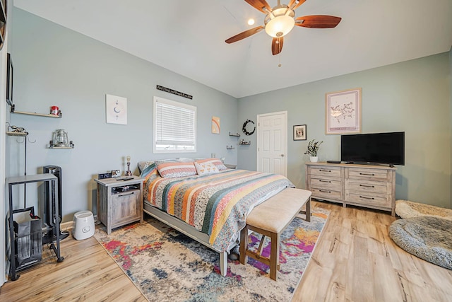 bedroom with a ceiling fan, vaulted ceiling, and light wood finished floors