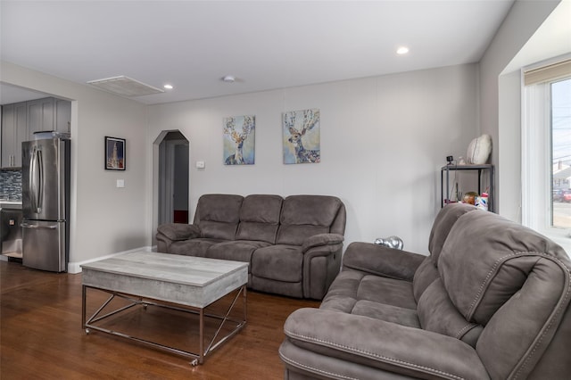 living room featuring arched walkways, dark wood-style flooring, visible vents, and recessed lighting