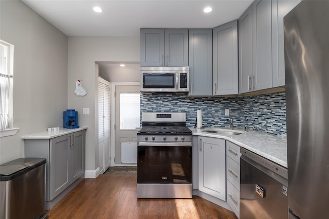 kitchen featuring gray cabinetry, light countertops, appliances with stainless steel finishes, backsplash, and dark wood-style floors