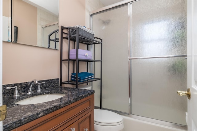 bathroom featuring vanity, toilet, and bath / shower combo with glass door