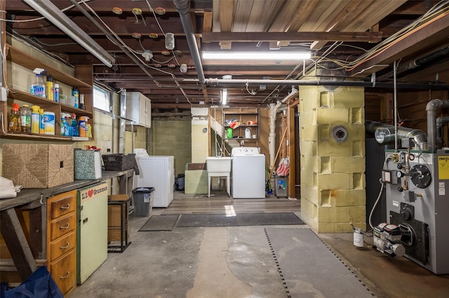 basement with washing machine and dryer, a heating unit, and a sink