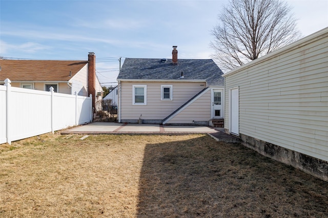 back of house with a yard, a shingled roof, fence, and a patio