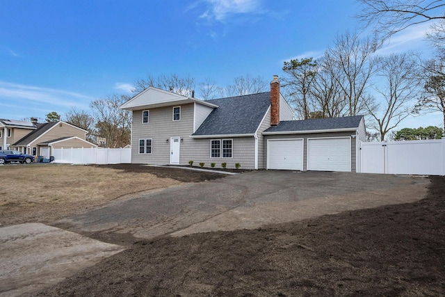 view of front facade featuring aphalt driveway, a chimney, a shingled roof, an attached garage, and fence