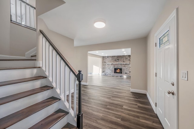 stairway featuring a fireplace, baseboards, and wood finished floors