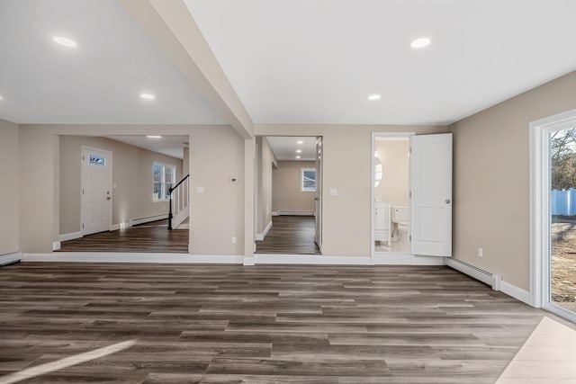 interior space featuring baseboards, stairs, a baseboard heating unit, and wood finished floors