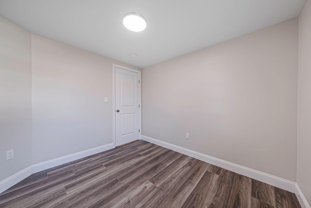 empty room featuring baseboards and dark wood-type flooring