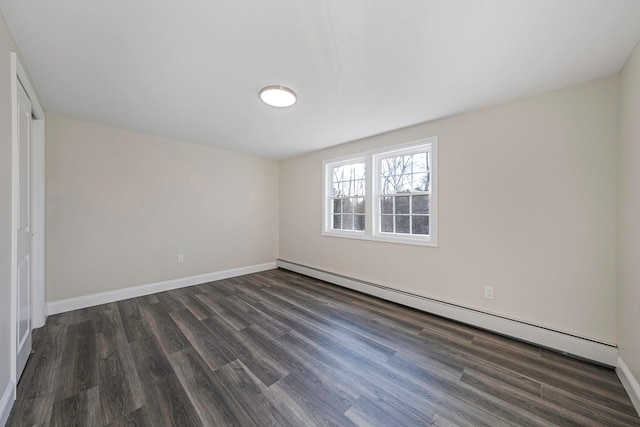 unfurnished room featuring a baseboard heating unit, dark wood-style flooring, and baseboards