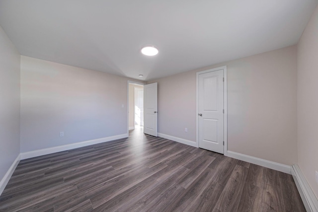 spare room featuring dark wood-style floors and baseboards