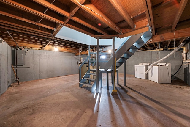 unfinished basement featuring washing machine and dryer, electric panel, and stairway