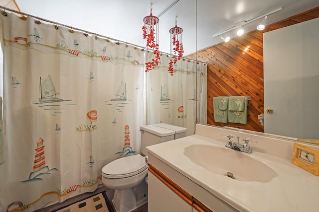 full bathroom with a shower with shower curtain, toilet, vanity, wood walls, and track lighting