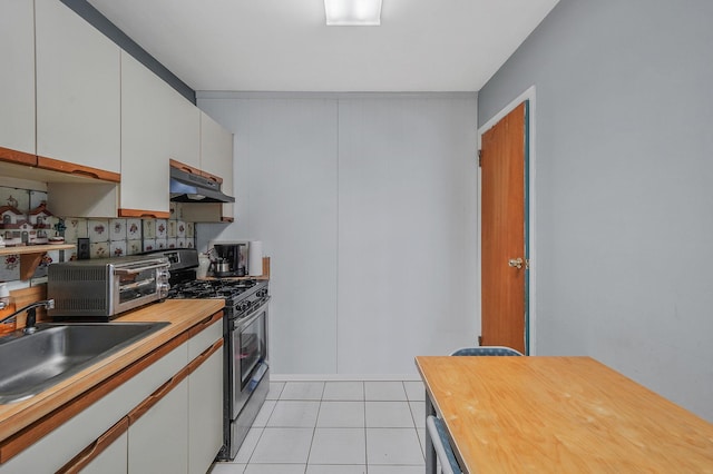 kitchen with gas range, wood counters, under cabinet range hood, a sink, and light tile patterned flooring