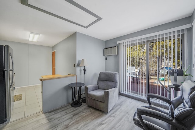 sitting room featuring a wall unit AC and light wood-style floors