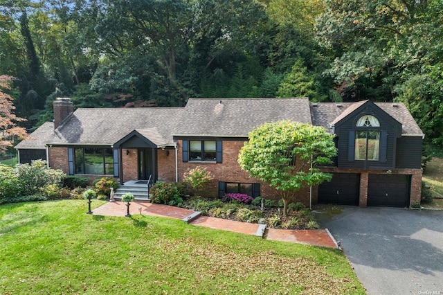 view of front of property featuring aphalt driveway, a front yard, brick siding, and a garage