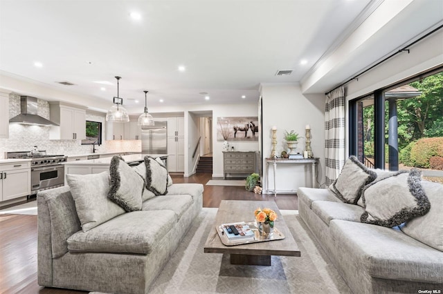 living area featuring stairs, a healthy amount of sunlight, visible vents, and wood finished floors