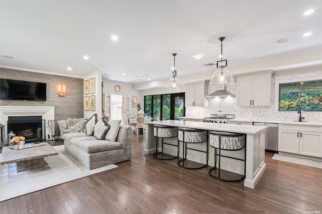 living area with dark wood-type flooring, recessed lighting, a fireplace, and ornamental molding