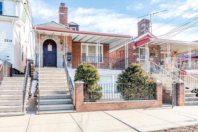 view of front of home featuring a chimney, stairway, a porch, and brick siding