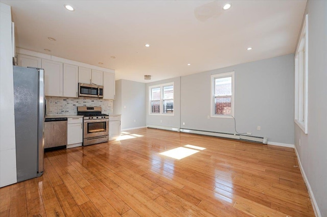 kitchen featuring stainless steel appliances, tasteful backsplash, baseboard heating, light wood-style floors, and white cabinetry