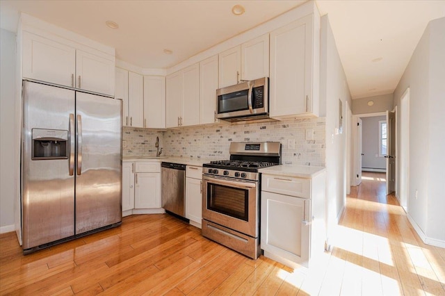 kitchen featuring decorative backsplash, light wood-style flooring, appliances with stainless steel finishes, light countertops, and white cabinetry