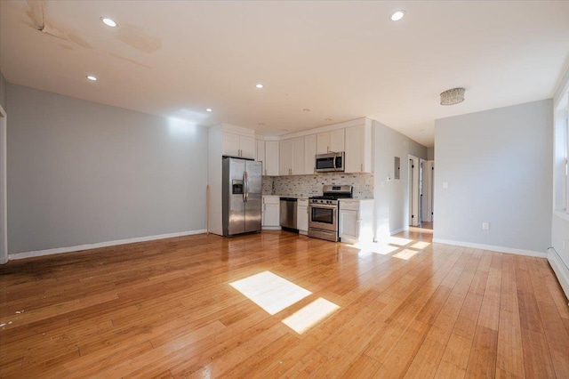 unfurnished living room with light wood-type flooring, baseboards, and recessed lighting