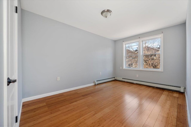 unfurnished room with a baseboard radiator, wood finished floors, and baseboards