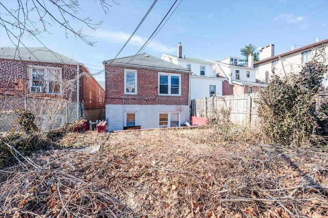 rear view of house featuring brick siding, fence, and a chimney