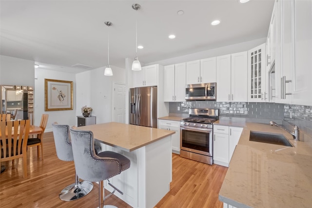 kitchen featuring a center island, a breakfast bar area, light wood-style flooring, appliances with stainless steel finishes, and a sink