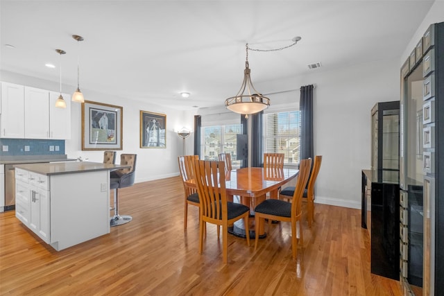 dining space with light wood-style floors, baseboards, and visible vents