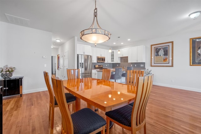 dining area featuring baseboards, visible vents, and light wood finished floors