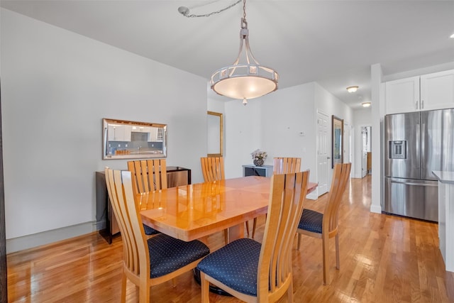 dining space featuring light wood-type flooring and baseboards