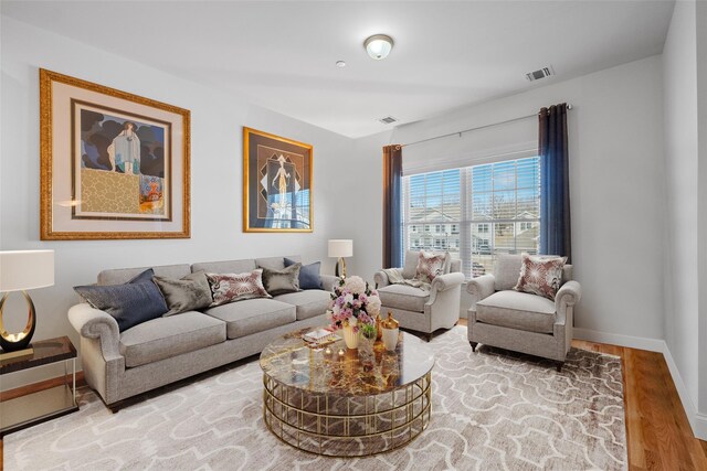 living area featuring light wood-type flooring, visible vents, and baseboards