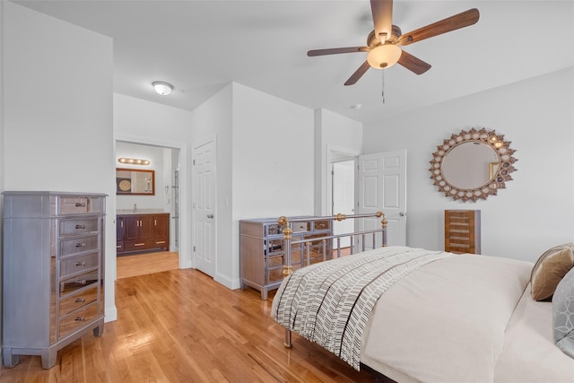 bedroom featuring light wood-type flooring, ceiling fan, baseboards, and ensuite bathroom