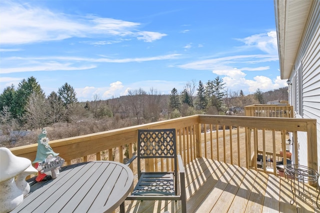 wooden deck with a forest view and outdoor dining area