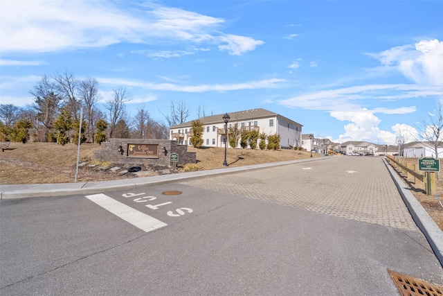 view of road featuring traffic signs, a residential view, curbs, and sidewalks