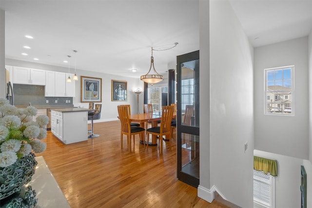 dining space featuring light wood-type flooring, baseboards, and recessed lighting