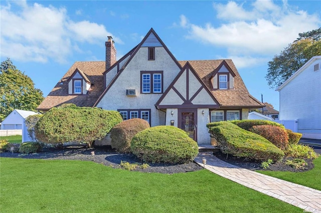 tudor house with a chimney, a front lawn, and stucco siding