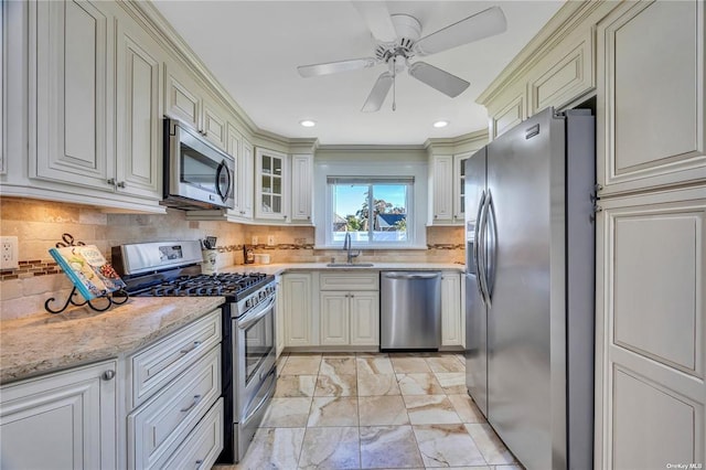 kitchen with stainless steel appliances, tasteful backsplash, glass insert cabinets, a sink, and light stone countertops