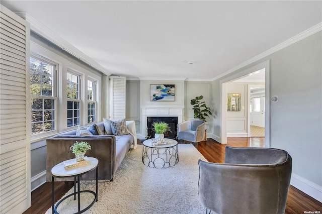 living area featuring dark wood-style floors, crown molding, a fireplace, and baseboards