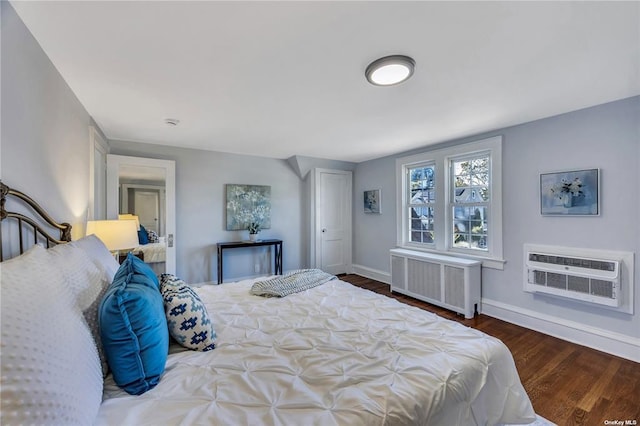 bedroom with radiator heating unit, a wall mounted air conditioner, wood finished floors, and baseboards