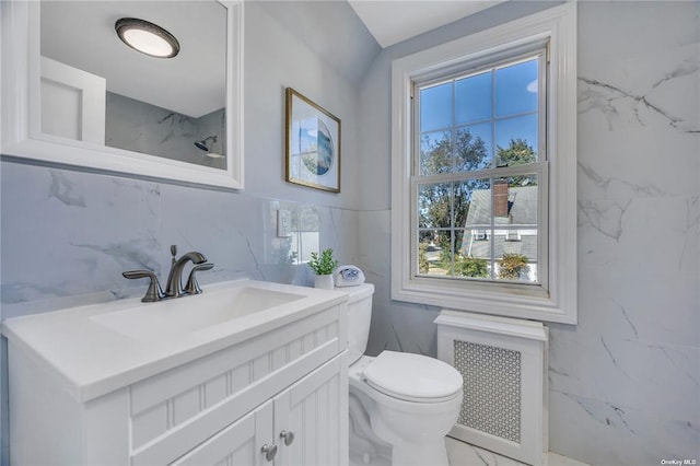 bathroom featuring marble finish floor, tile walls, toilet, radiator heating unit, and vanity