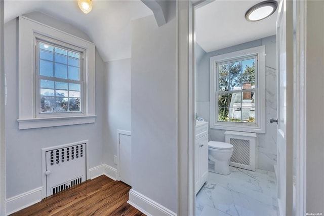 bathroom featuring toilet, baseboards, vaulted ceiling, marble finish floor, and radiator