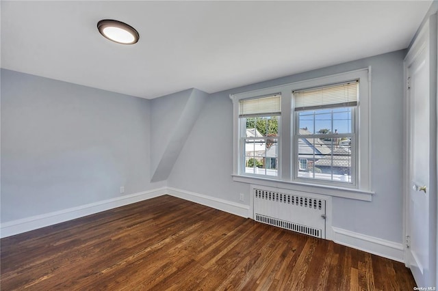 additional living space with radiator, dark wood finished floors, and baseboards