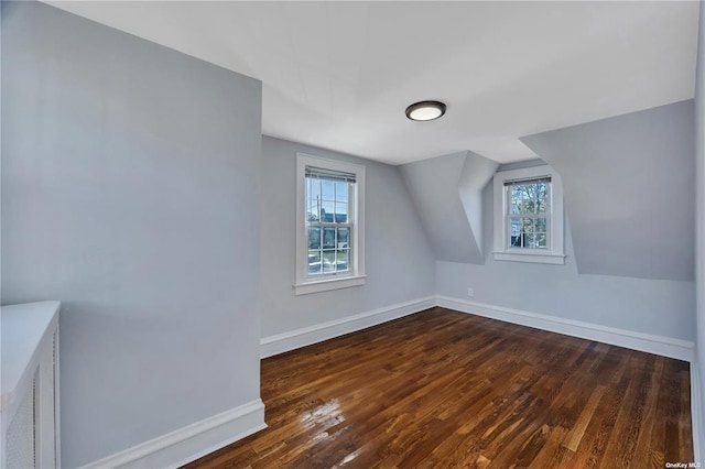 additional living space with dark wood finished floors and baseboards