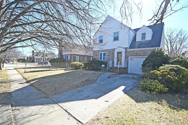 view of front of property featuring stone siding, fence, and concrete driveway