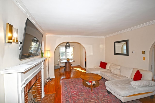 living area featuring crown molding, arched walkways, and wood finished floors