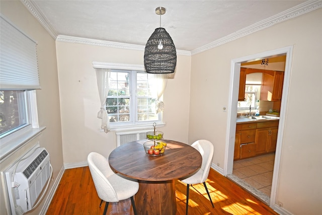 dining area featuring an AC wall unit, ornamental molding, wood finished floors, and baseboards